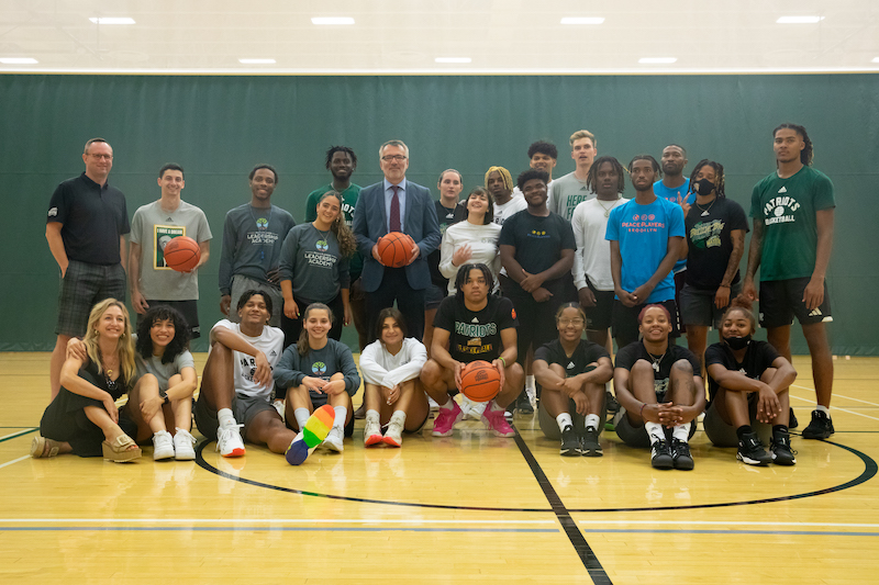 Photo of Dean Ozerdem with PeacePlayers, men's and women's basketball teams, and students