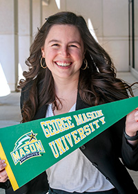 Averi Jordan smiling and holding a George Mason University pennant.