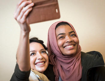 Two students taking a selfie picture together while smiling