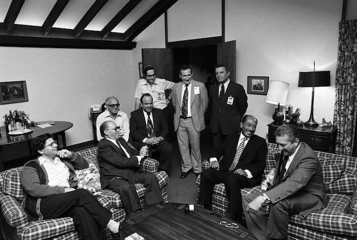 Menachem Begin and Anwar Sadat congregate with their advisors in a cabin at Camp David at the conclusion of the Camp David Accords.