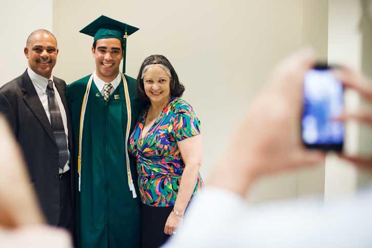 A graduating student poses for a photo with their parents