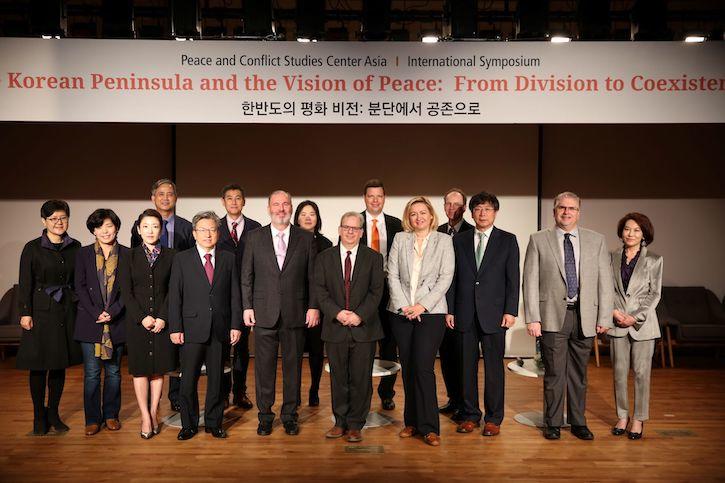 People standing together at a conference under the banner: Korean Peninsula and the Vision of Peace: From division to coexistence